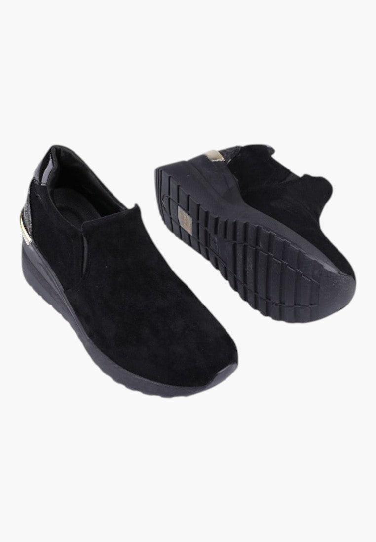 Szczegółowy widok boku czarnych sneakersów damskich na koturnie z białym tłem