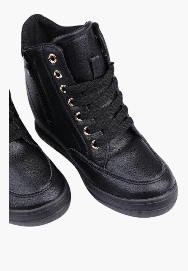 Zbliżenie na detale czarnych sneakersów damskich z złotymi oczkami.