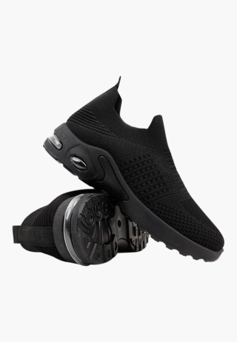 Szczegół grubej podeszwy czarnych wsuwanych sneakersów na białym tle