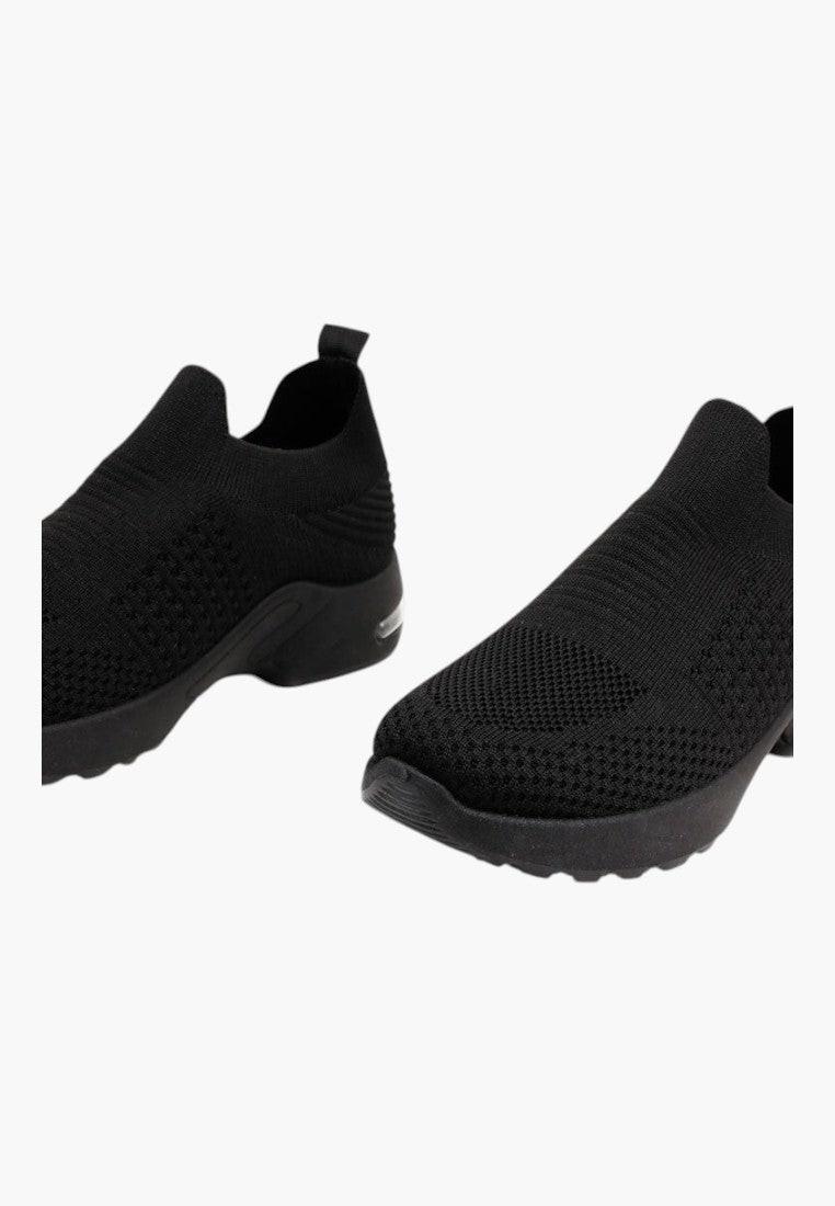 Szczegół elastycznej podeszwy czarnych wsuwanych sneakersów z dzianiny