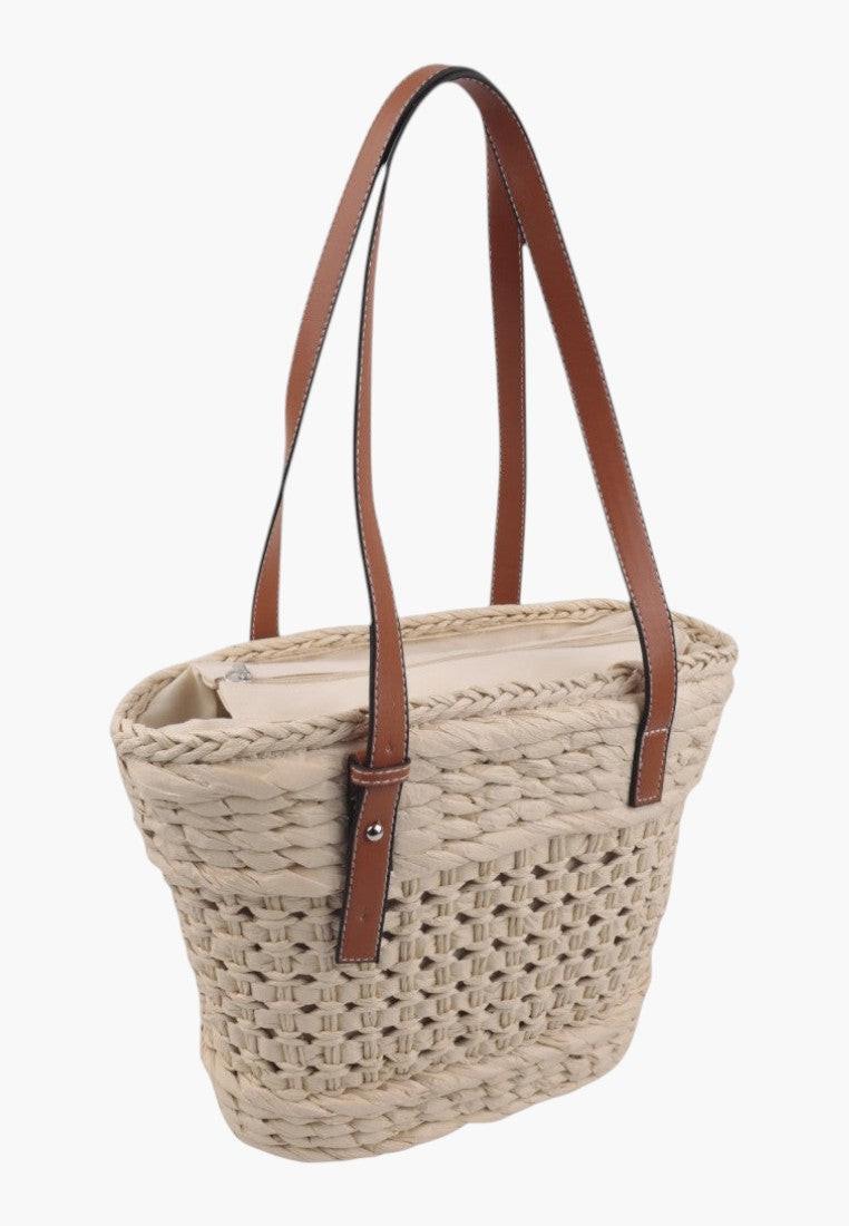 Widok z boku słomkowej torebki shopper w kolorze beżowym i brązowym z plecionym wzorem.