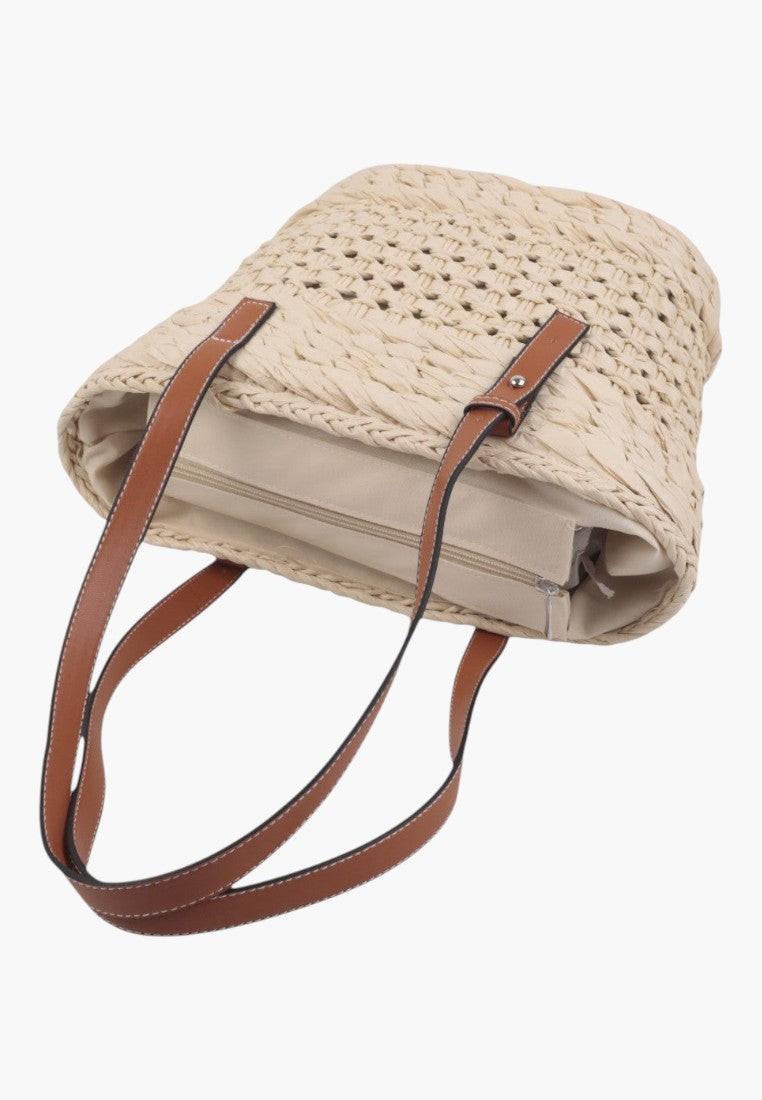 Zbliżenie na plecioną torebkę shopper w kolorze beżowym i brązowym.