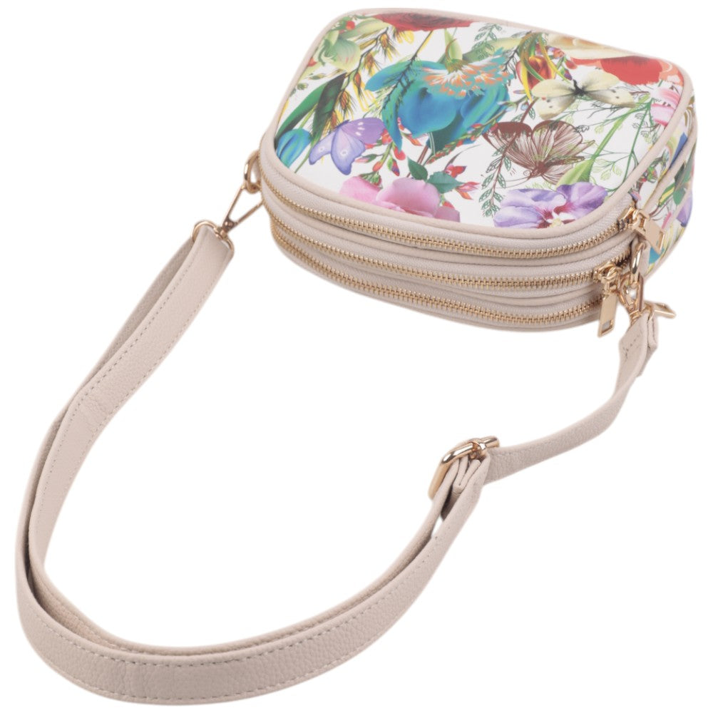 Zbliżenie na torebkę crossbody z kwiatowym wzorem i zamkami.