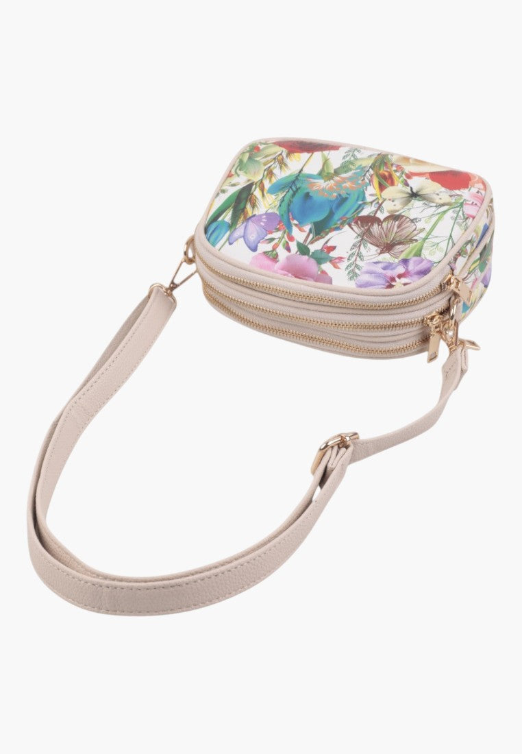 Zbliżenie na torebkę crossbody z kwiatowym wzorem i zamkami.