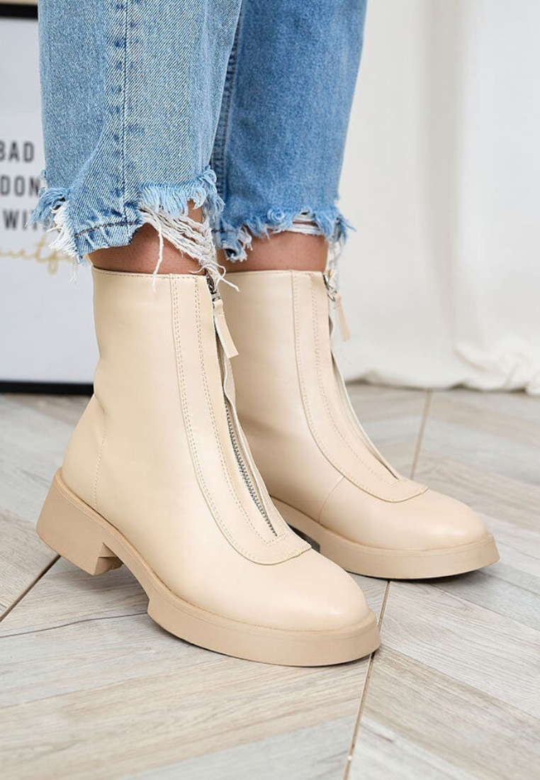 Falio beige insulated ankle boots made of eco-leather with a front zipper, worn with blue frayed jeans.