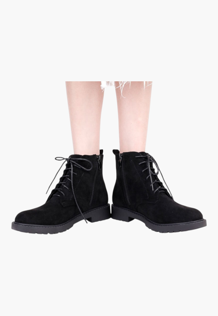 Falio black faux suede ankle boots with flat soles, side zippers, and front lace-up closure on a model