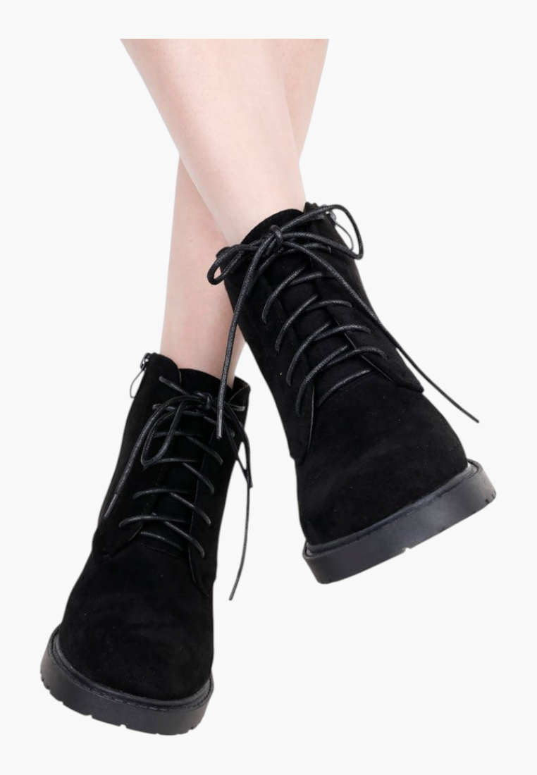 Falio black faux suede ankle boots with flat soles, front laces, and side zipper closure on a model