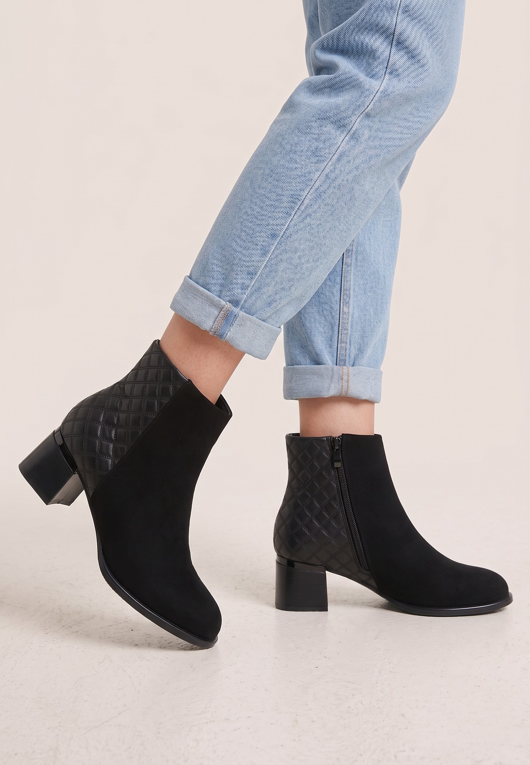 Falio black faux suede ankle boots with quilted heel detail, block heel, and side zipper worn with blue jeans.