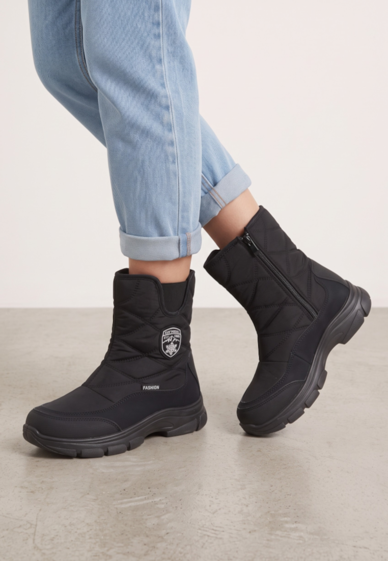 Falio black quilted softshell snow boots with side zippers and thick soles worn with light blue jeans