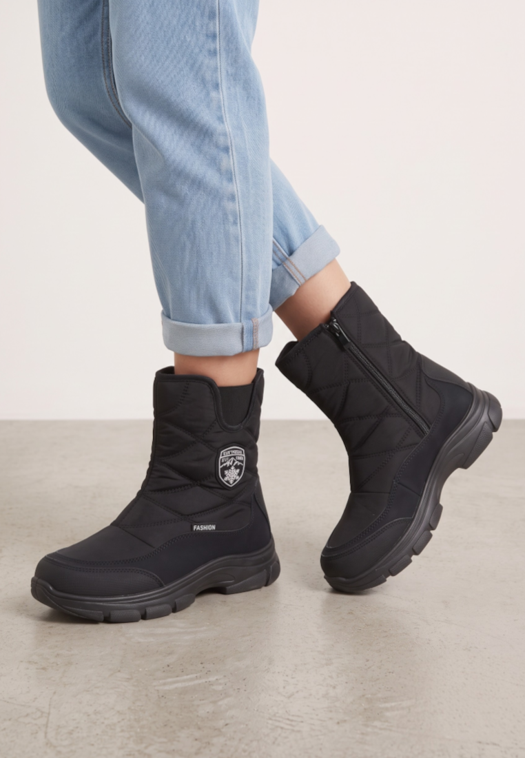 Falio black quilted softshell snow boots with side zippers and thick soles worn with light blue jeans