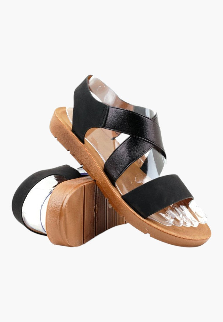 Falio black slip-on sandals with crisscross straps, open toe, and thick tan rubber sole for women