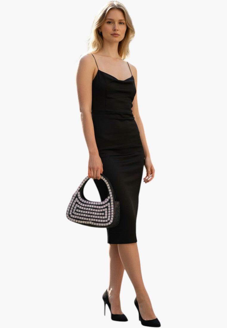 Falio black satin slip dress with cowl neck and embellished handbag, worn by a model on a city street.