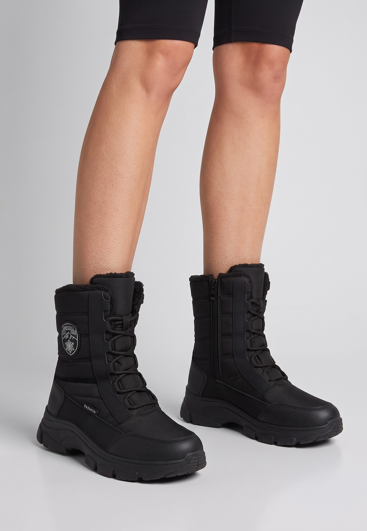 Falio women's black softshell snow boots with quilted high-top, front lacing, side zipper, and thick lug sole.