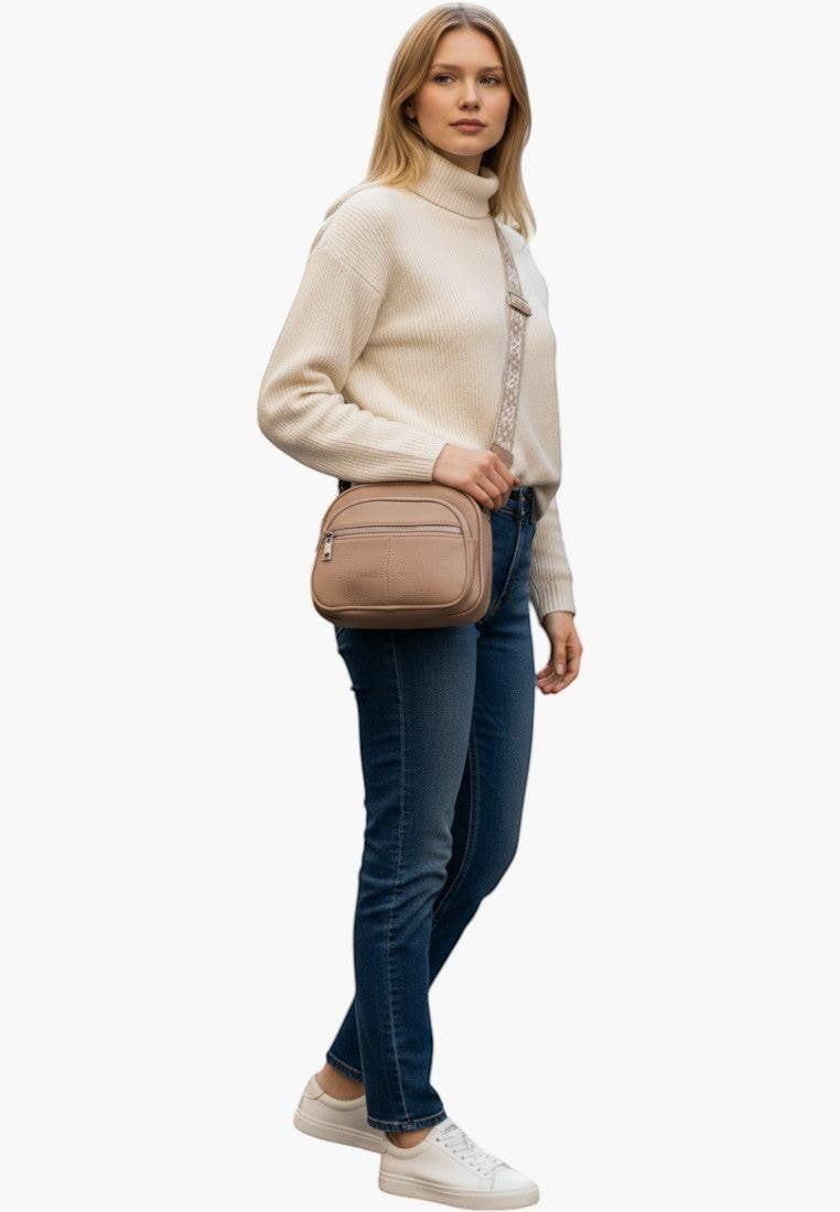Falio brown crossbody bag made of eco-leather with a zip closure and 5 pockets, worn by a woman on a city street.
