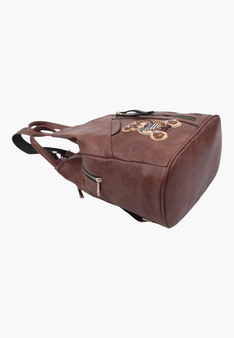 Falio brown faux leather urban backpack with a decorative bear patch and multiple zippered pockets