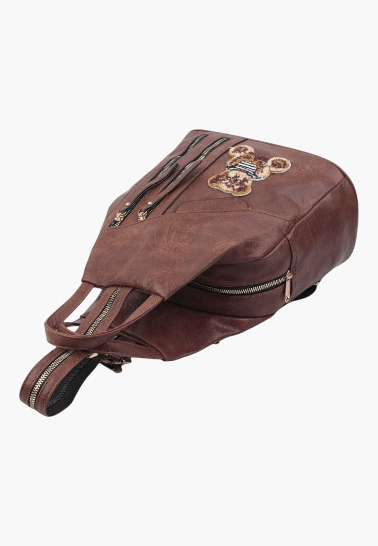 Falio brown faux leather urban backpack with a decorative teddy bear patch and multiple zippered compartments.