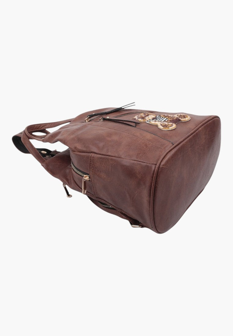 Falio brown faux leather urban backpack with multiple zippered pockets and decorative bear patch detail