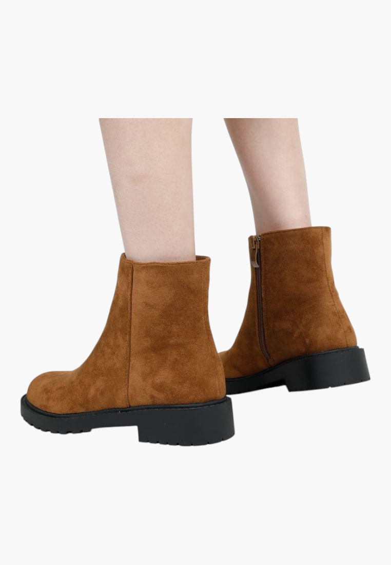 Falio brown suede ankle boots with a side zipper and chunky black lug sole worn on feet