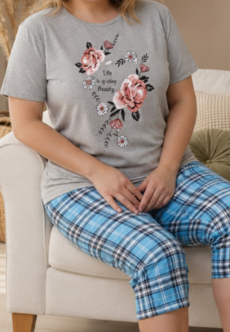 Falio cotton women's pajama set with a grey floral print t-shirt and blue plaid capri pants, worn by a smiling woman.