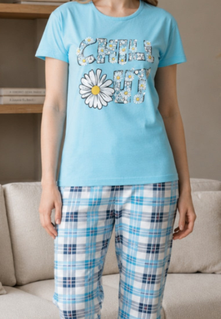 Falio cotton women's pajama set with a light blue graphic t-shirt and blue plaid capri pants in a cozy living room.