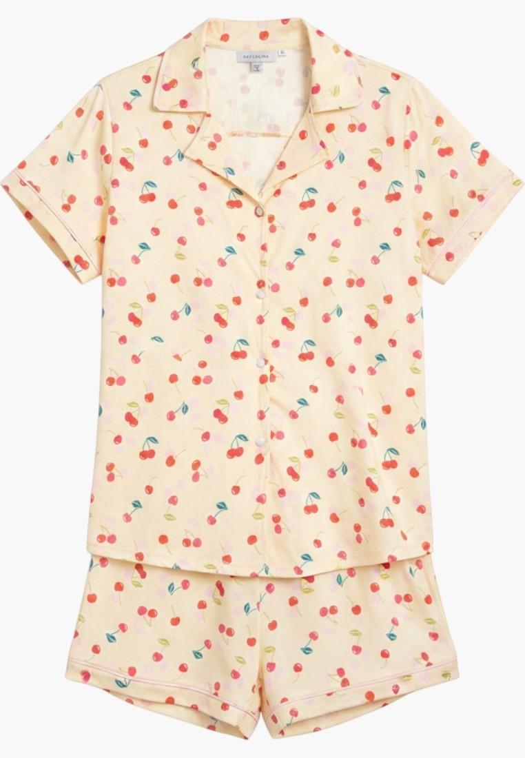 Falio women's short pajama set in cream with a red cherry print. Features a collared, button-up top and short bottoms, made of 100% cotton.
