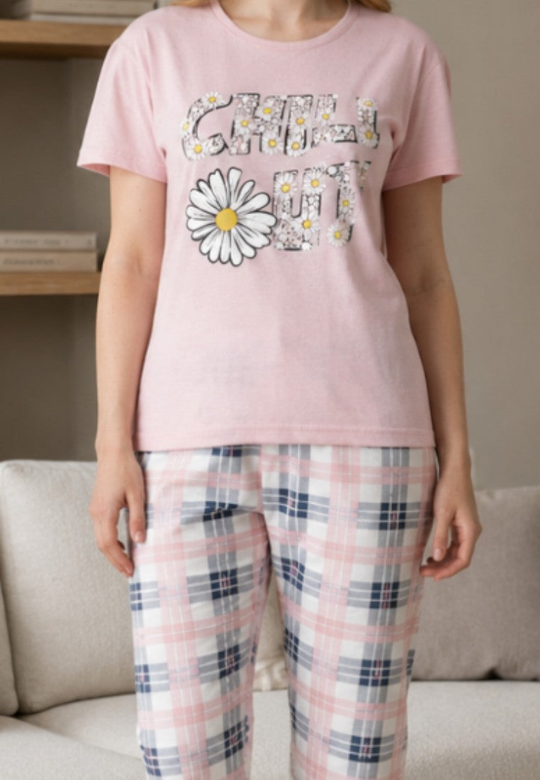 Falio women's pink cotton pajama set with a floral graphic t-shirt and plaid capri pants in a cozy living room.