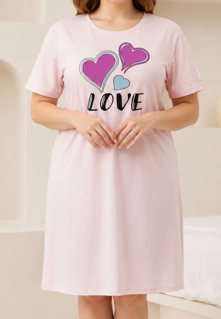 Falio light pink short-sleeve nightgown with heart graphics and LOVE text, worn by a woman in a bedroom.
