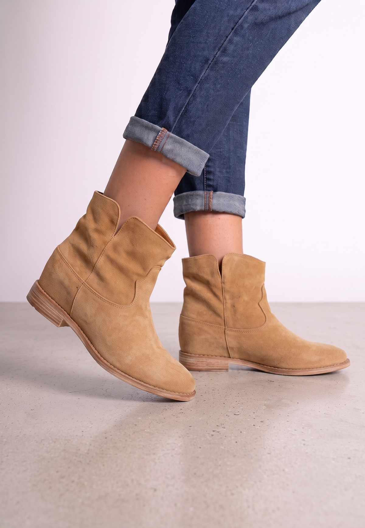 Falio tan faux suede ankle boots with a hidden wedge heel and western-inspired design worn with blue jeans.