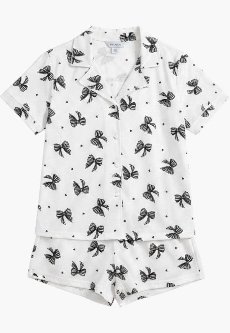 Falio white 100% cotton women's pajama set with black bow print, short sleeves, shorts, and V-neck.