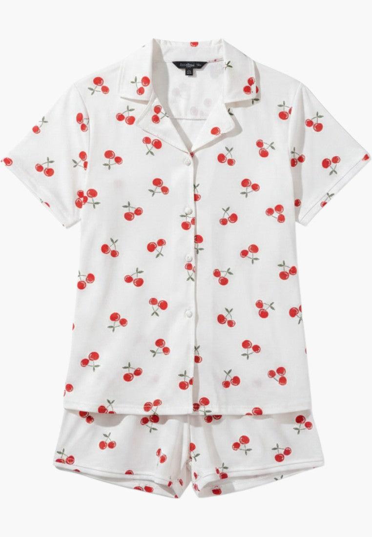 Falio white 100% cotton women's pajama set with red cherry print, short sleeves, shorts, and V-neck. Model is wearing size M.