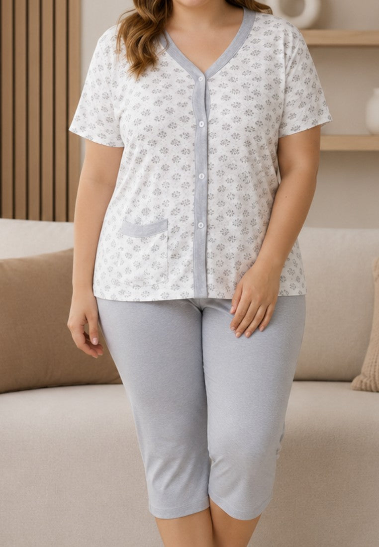 Falio cotton women's pajama set with a floral button-up top and grey capri pants, worn by a smiling woman in a lounge.