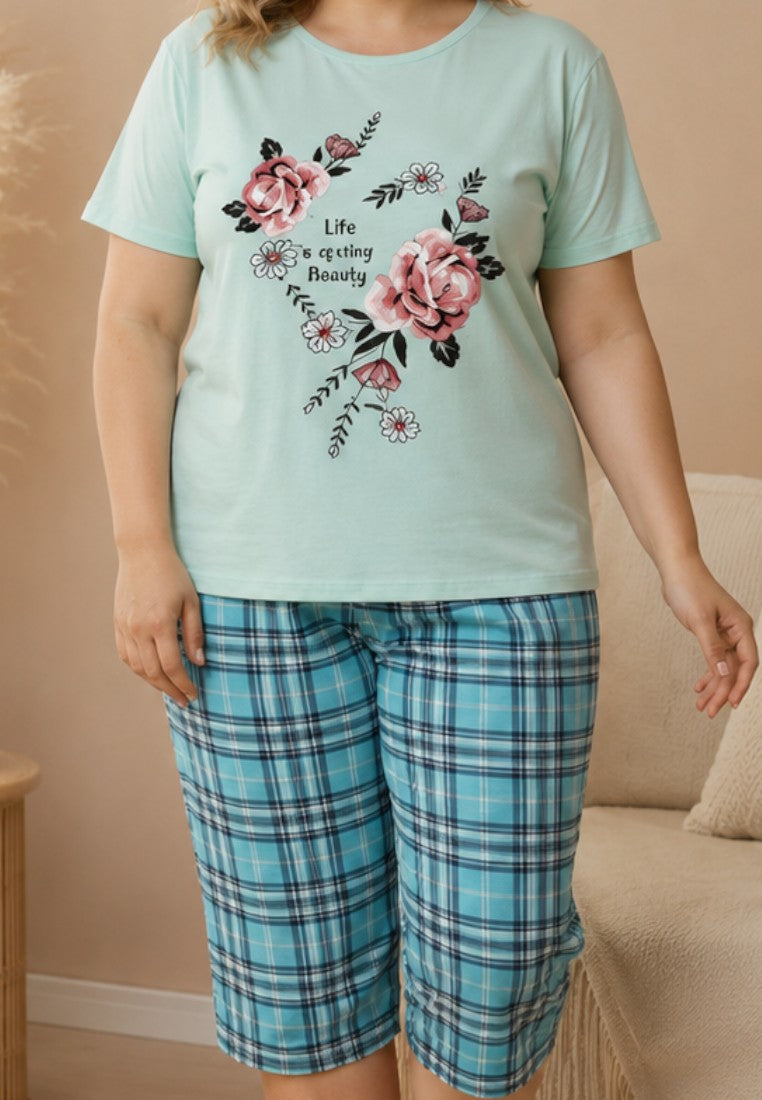 Falio women's cotton pajama set with a mint floral t-shirt and blue plaid capri pants in a cozy living room.
