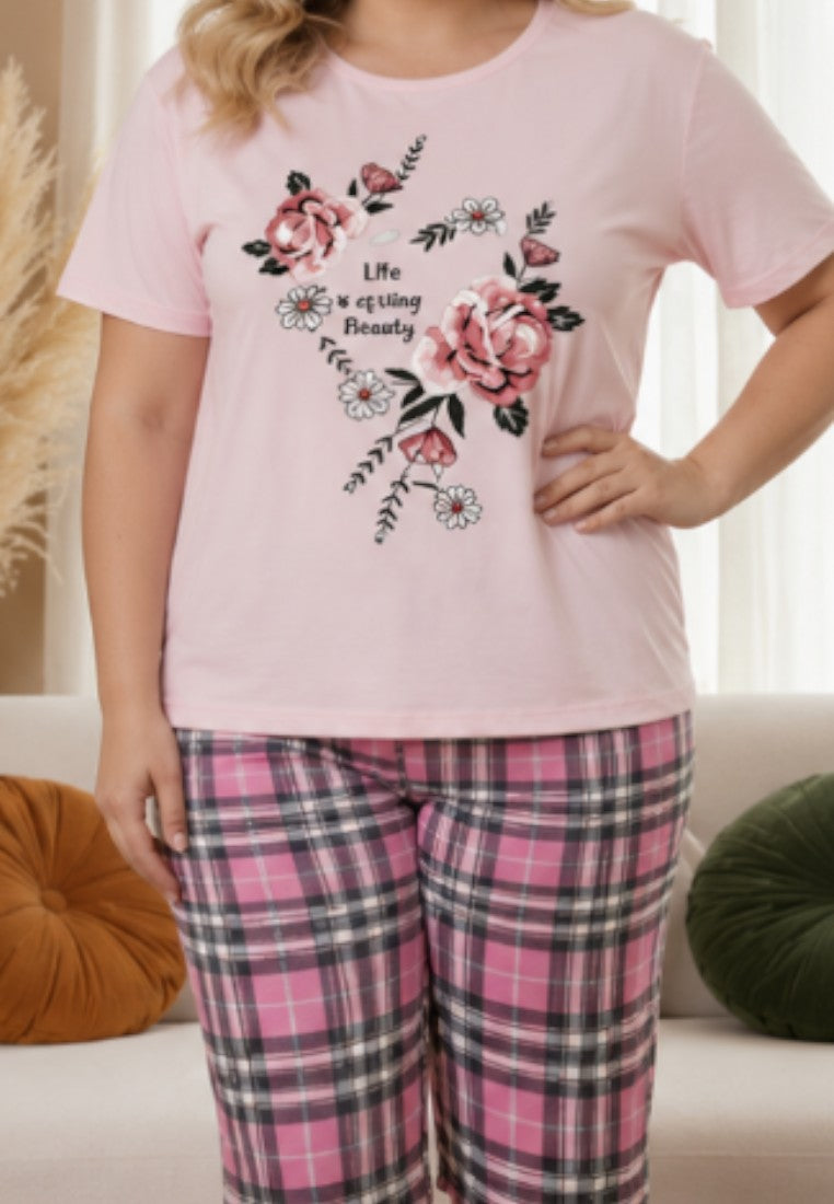 Falio women's cotton pajama set with a pink floral print t-shirt and plaid capri pants worn by a smiling model.