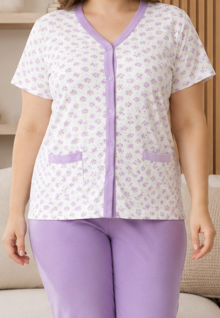 Falio women's cotton pajama set with a floral button-down top and solid purple capri pants in a cozy living room.