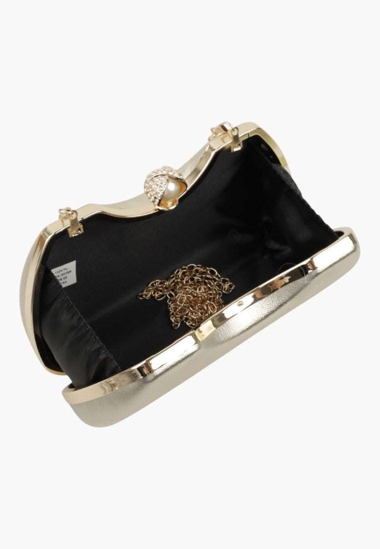 Detail view of a black and gold clutch handbag with a metal frame and snap closure.