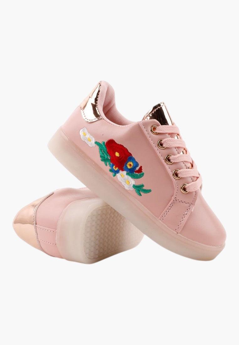 Stylowe jasno różowe buty sportowe z haftowanymi kwiatami w ujęciu lifestyle.