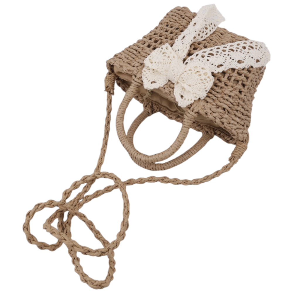 Detail shot of a brown and white woven handbag with a bow detail and long strap.