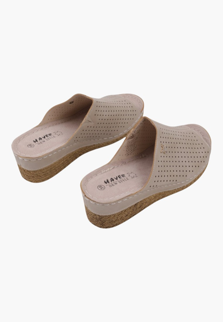 Boczne ujęcie beżowych klapek damskich z zamkniętym tyłem i stylem slip-on na białym tle
