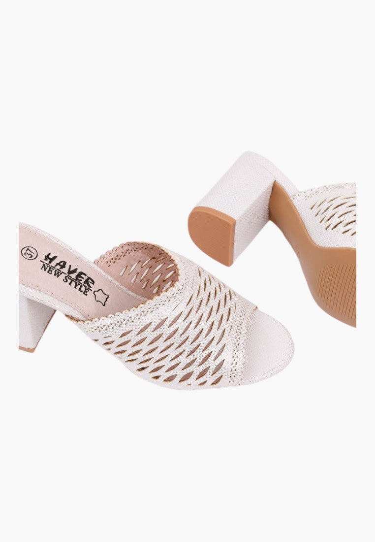 Detail close-up of white heeled sandals with cut-out design and chunky heel on a white background