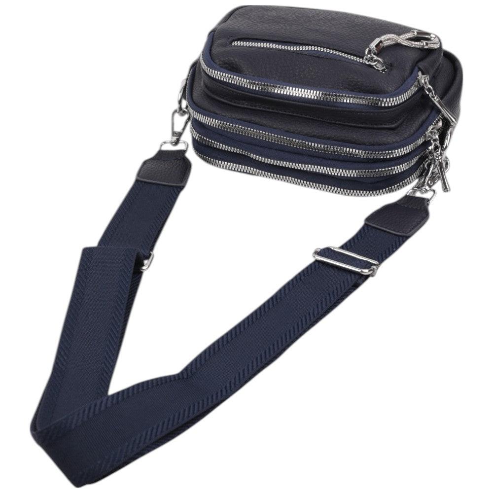 Close-up detail of a navy crossbody bag featuring a double zipper and textured fabric.