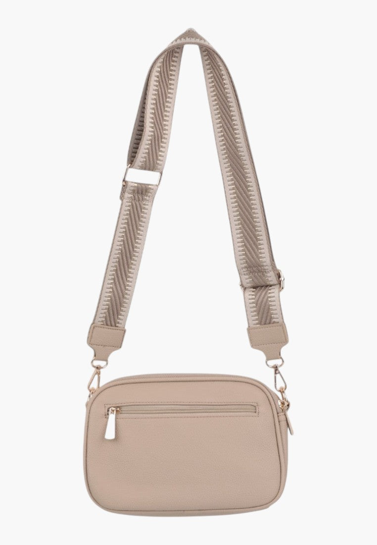 Lifestyle shot of a khaki crossbody bag showing adjustable strap and logo detail.