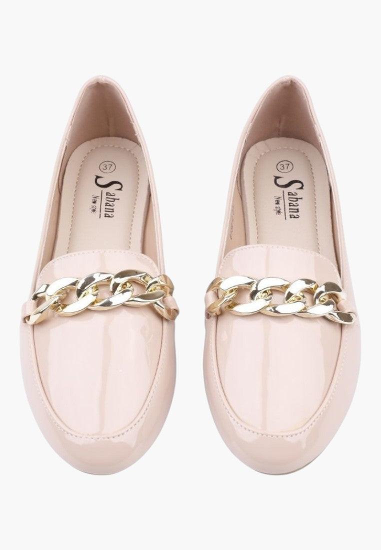Close-up detail of pink slip-on shoes showcasing soft material and gold chain.