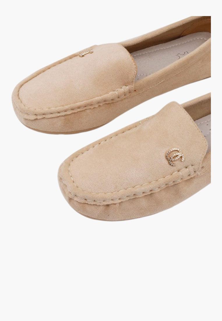 Close-up detail of stitching on beige slip-on shoes.