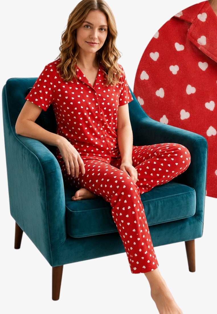 Lifestyle shot of a red polka dot pajama set with short sleeves on a natural background.