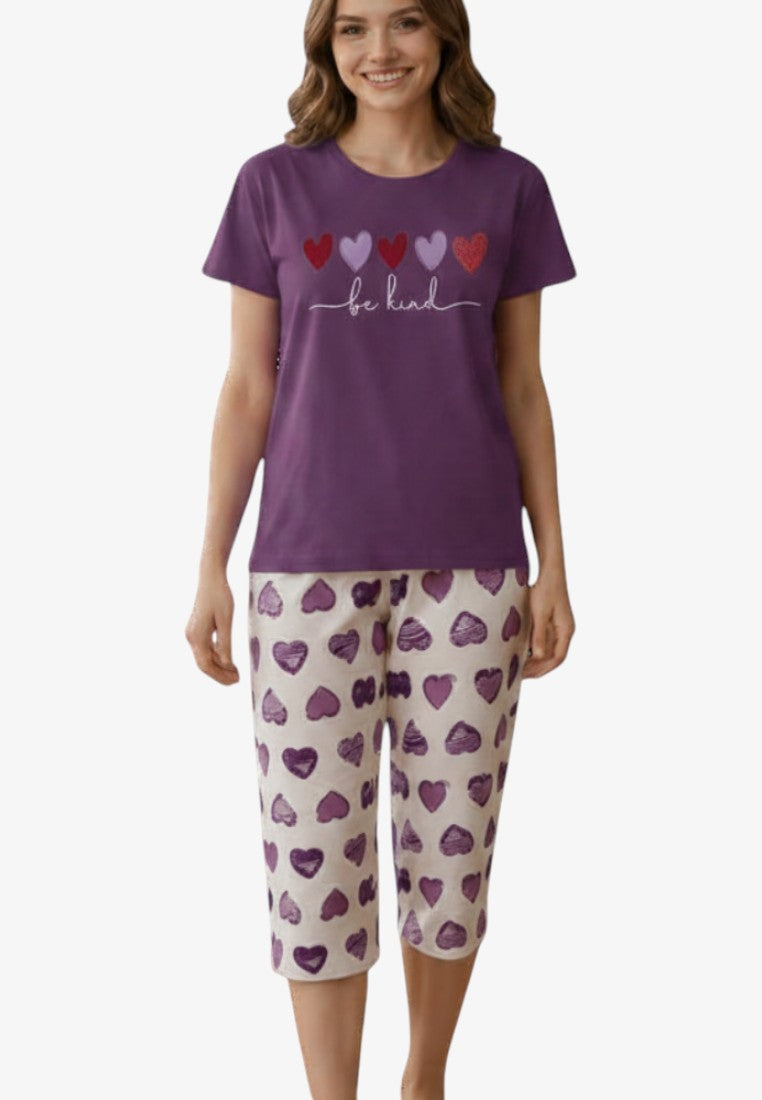 Lifestyle shot of a women's pajama set featuring a heart print in purple, white, and red.