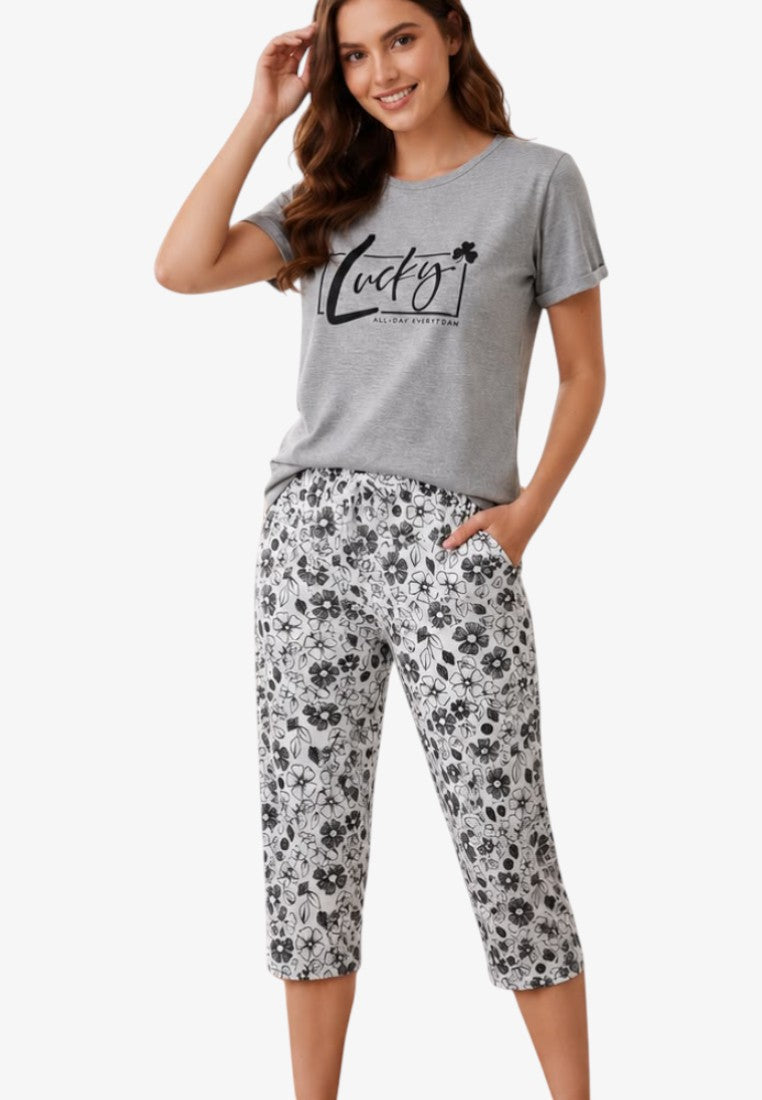 Lifestyle shot of a women's pajama set featuring a graphic tee and patterned pants in gray and black.