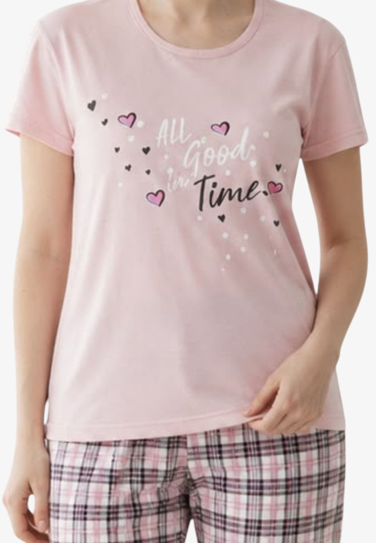 Detail close-up of a pink pajama top featuring a graphic print and short sleeves on a white background.
