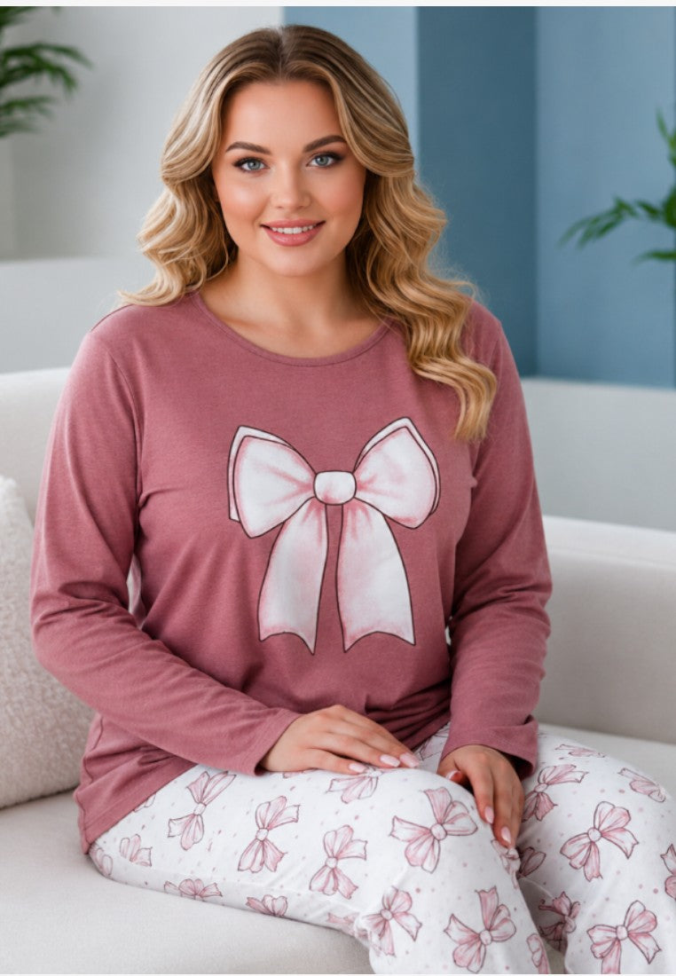 Lifestyle shot of plus size cotton pajama set featuring pink bow print on mauve background.
