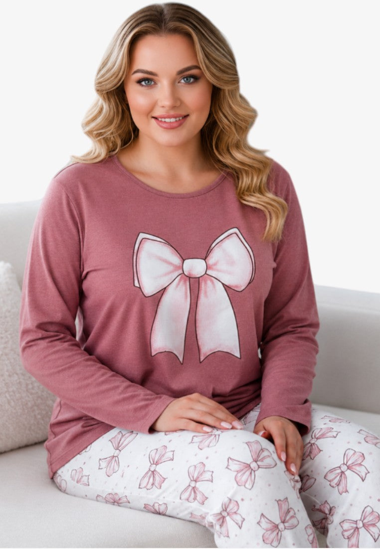 Lifestyle shot of plus size cotton pajama set with long sleeves and pink bow print on dusty rose top.