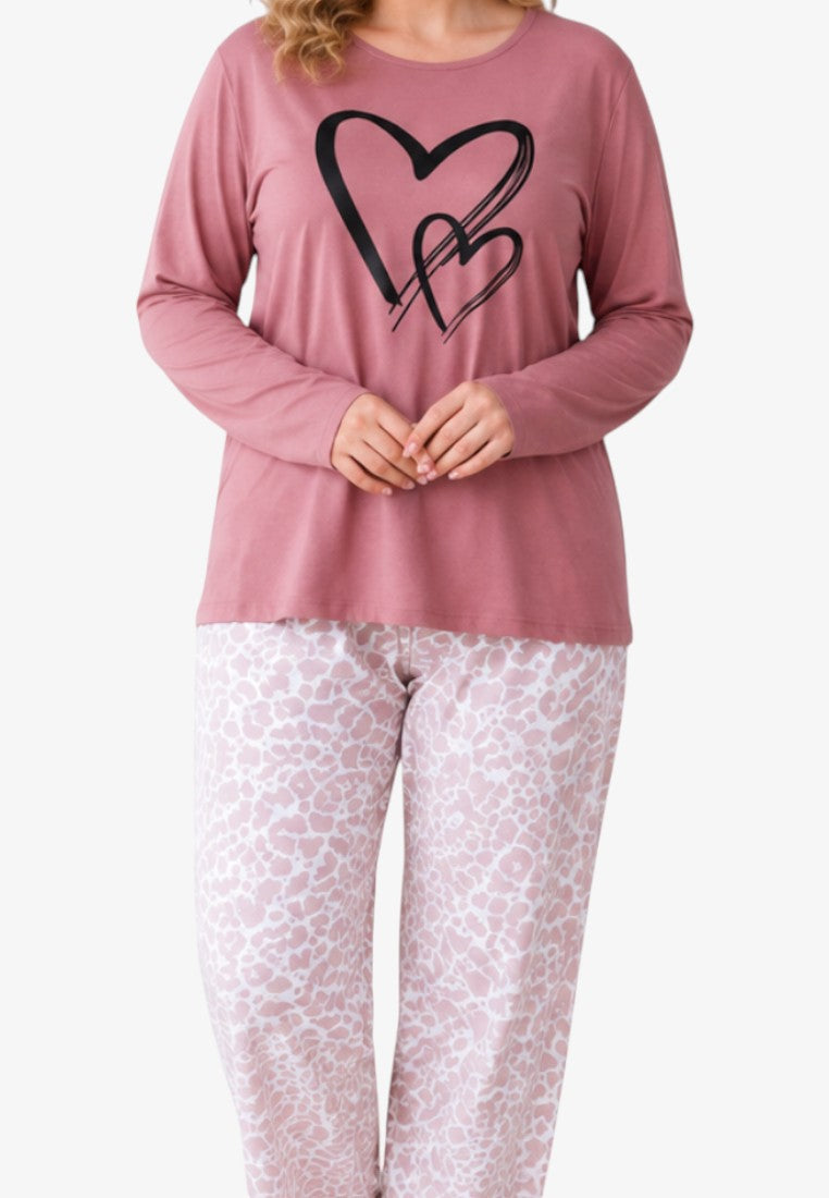 Lifestyle view of a plus size cotton pajama set featuring a dusty pink heart print top and patterned trousers.